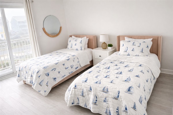 Bright beach front guest bedroom featuring two twin beds and waterfront balcony