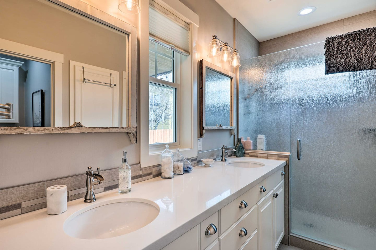 Dual vanities and a glass rain shower turn getting ready into a small luxury.