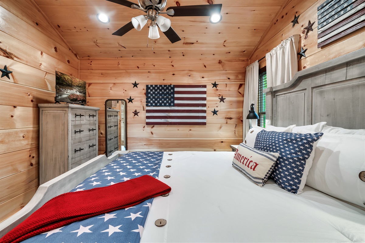 Americana themed bedroom with king bed, en-suite bathroom and 32 inch smart TV.