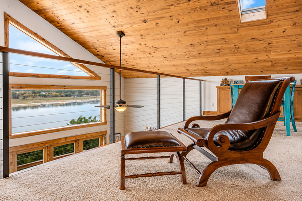 Relax in the cozy loft overlooking Lake Travis, where soaring wood ceilings, expansive windows, and a comfortable reading nook create the perfect place to unwind while enjoying beautiful lake views.
