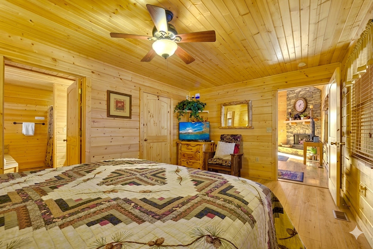 Bedroom #1 - Wake up to the charm of cabin living with a peek into the inviting living room beyond. A perfect space to unwind, catch a show, or simply enjoy the quiet hum of the mountains.