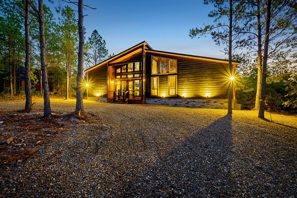 A stunning modern cabin retreat glowing warmly under the forest canopy.