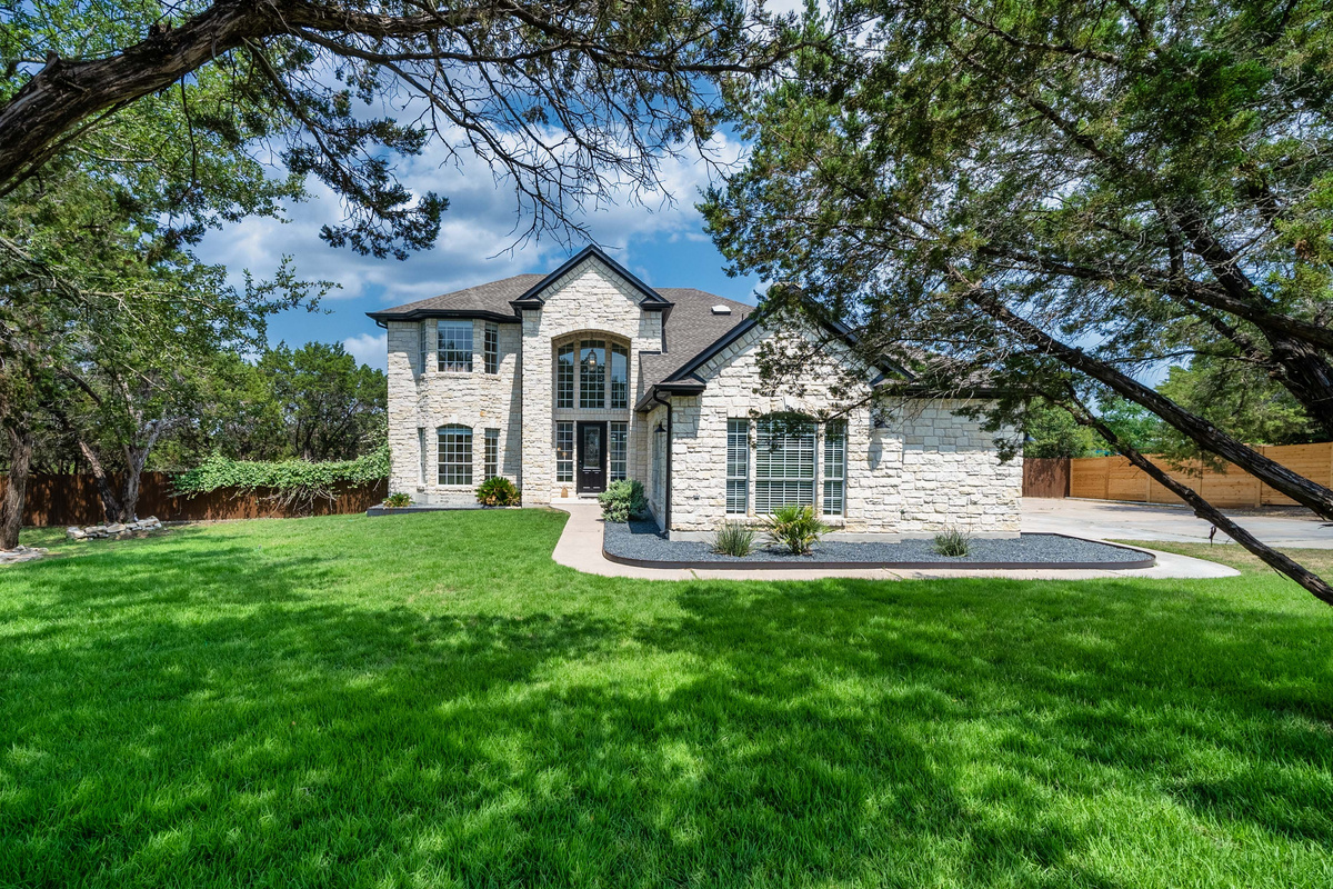 Grand stone exterior framed by a sprawling green lawn.