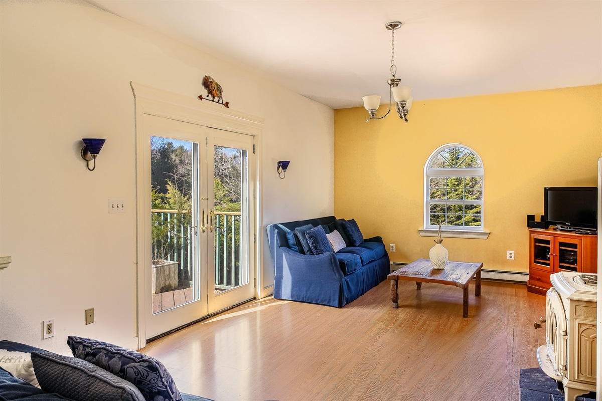 Relax in the bright, open living room featuring a Roku Smart TV and French doors that lead to the large back deck. This inviting space offers a seamless transition to the outdoors, perfect for enjoying the fresh air of the Acadia National Park region.