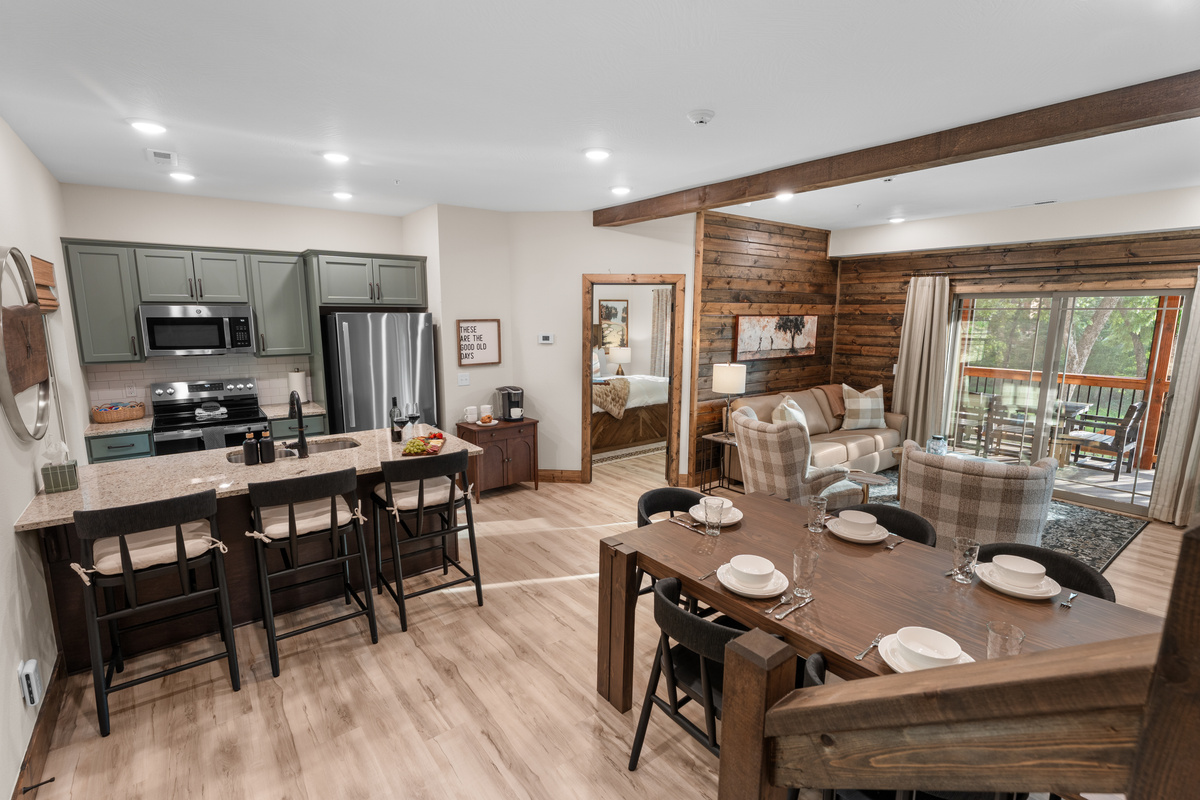Walk in the front door to gather in the open great room where kitchen, dining, and living flow together under wood-beam ceilings.