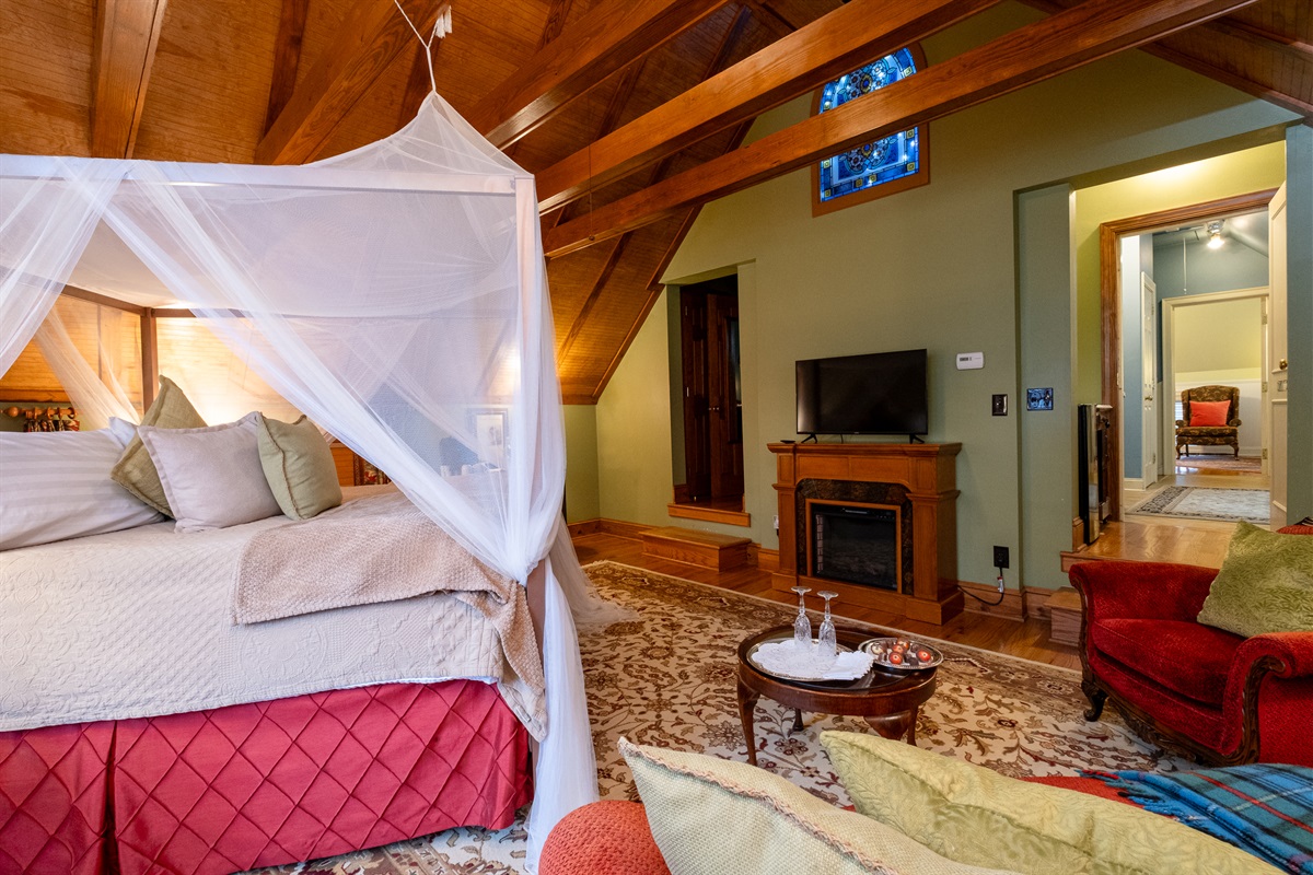 Bedroom view highlighting the draped canopy, hardwood floors, and adjoining living space.