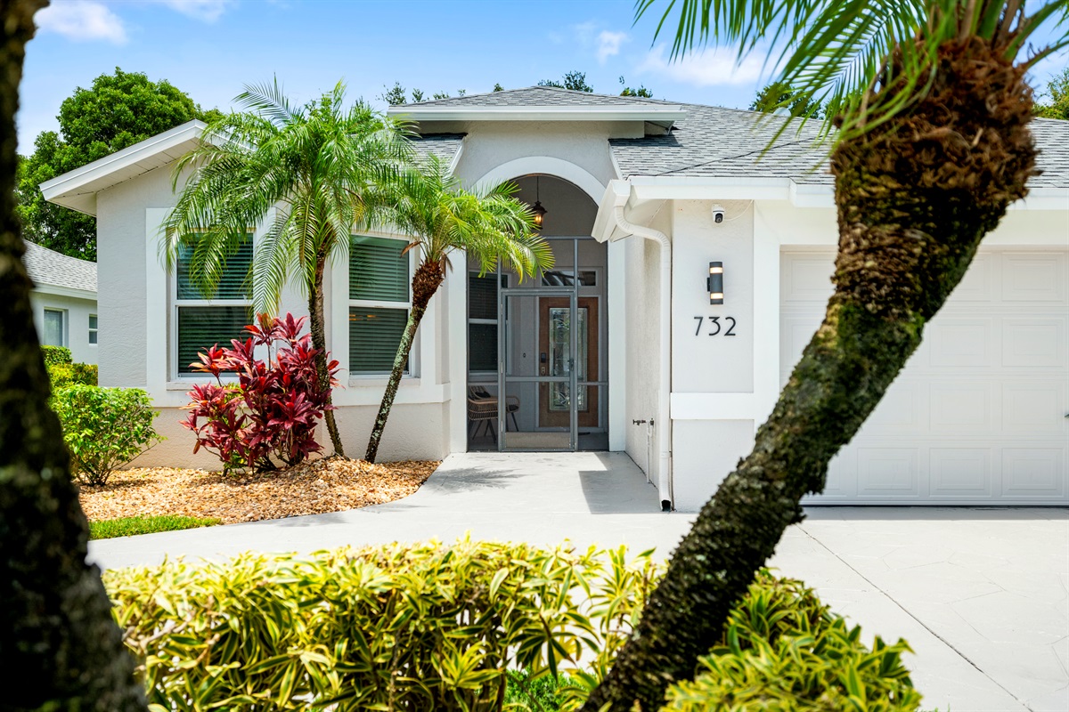 Tropical entry with swaying palms and a screened front porch for breezy arrivals