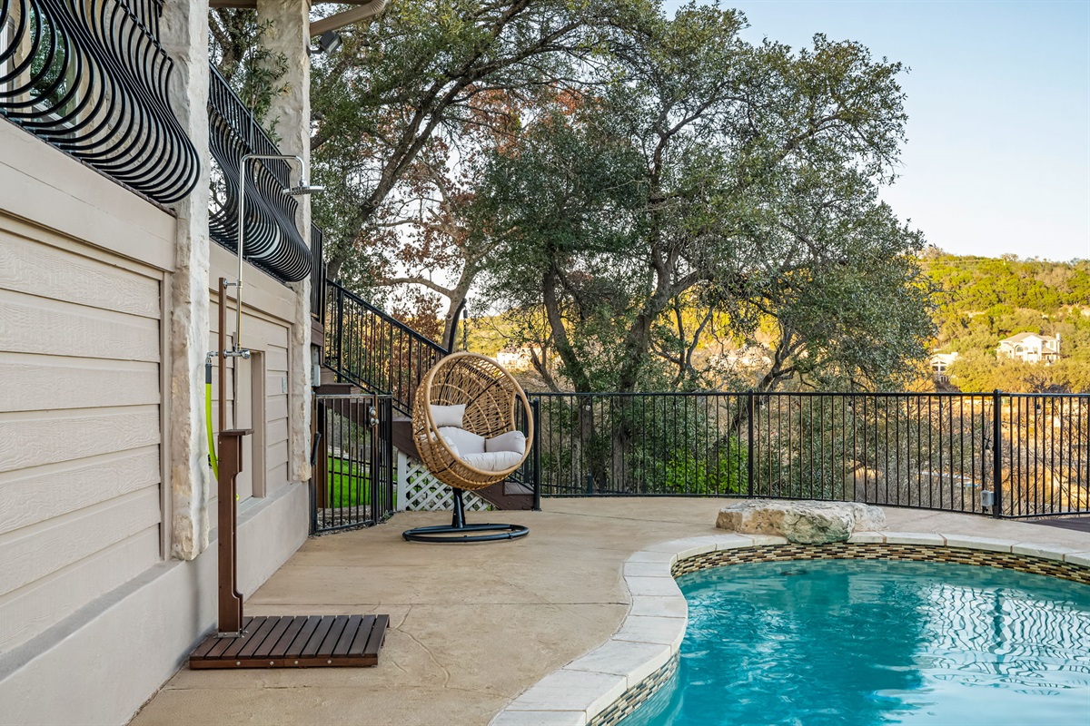 Poolside patio with cozy hanging chair — perfect for relaxing outdoor moments.