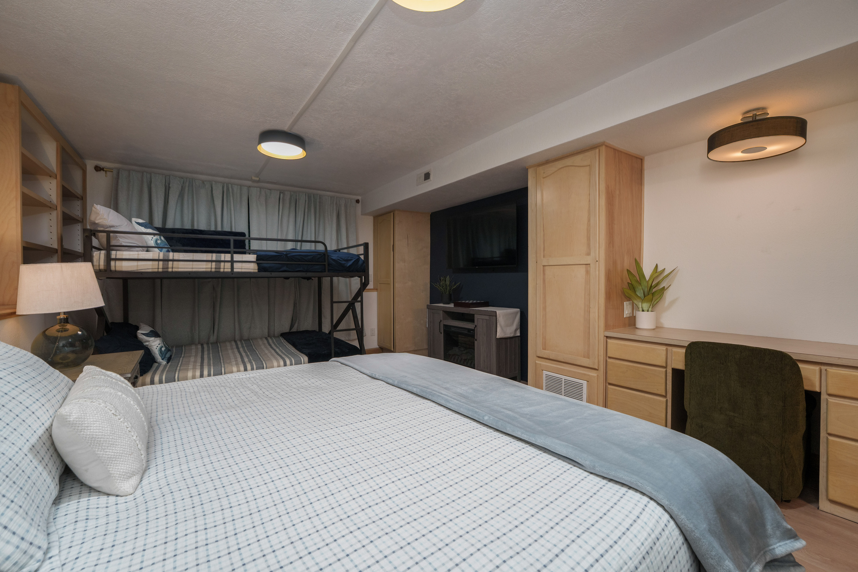 Bedroom 2 is thoughtfully designed for families and groups, featuring a queen bed, a queen-over-queen bunk bed, a dedicated remote-work desk, and a private ensuite bathroom (Bathroom 2)