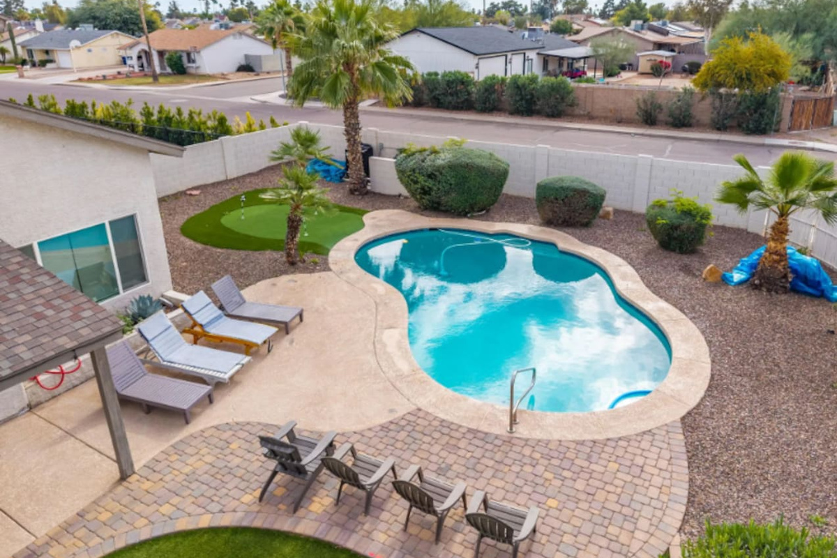Resort-style backyard with sparkling pool, spa, putting green, and multiple lounging areas.
