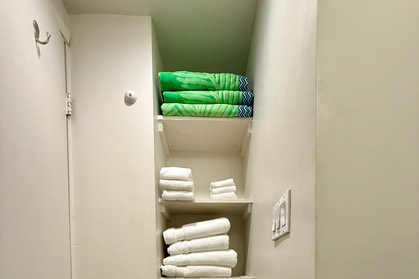 Shelves behind bathroom door include plush beach towels and bath towels in addition to a complementary set of starter toiletries, hand soap and toilet paper.