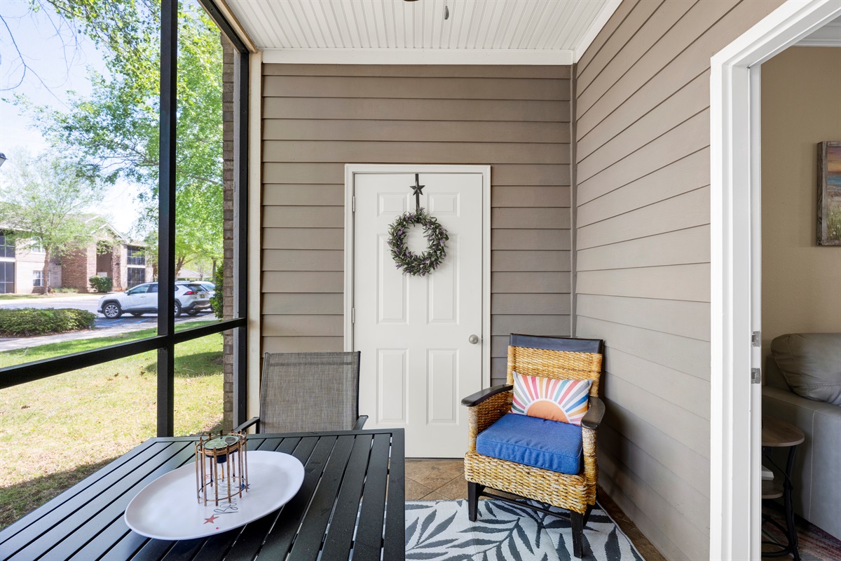 Covered screened in porch area with seating and table 