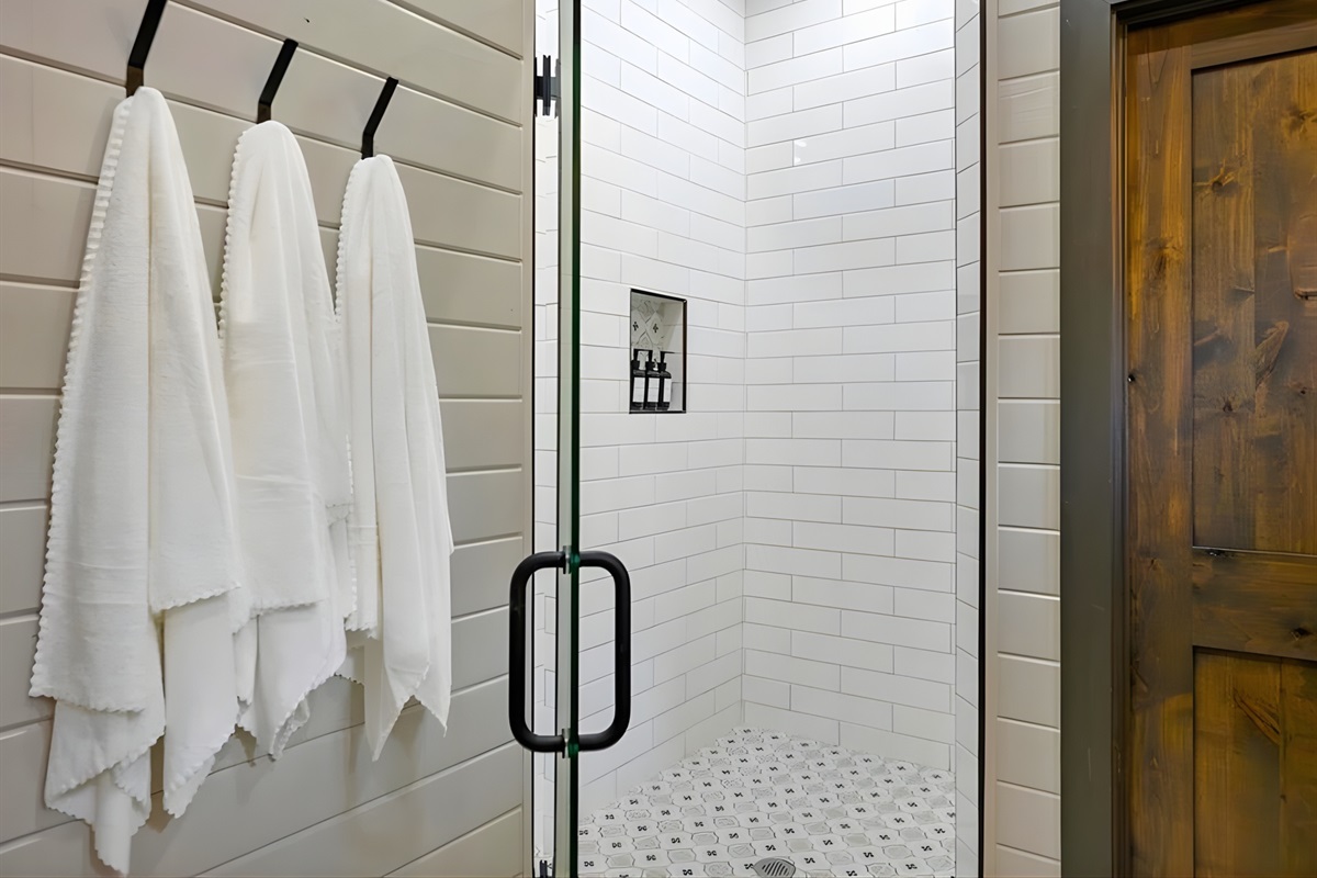 Crisp white towels and sleek glass shower doors give the bathroom a fresh, polished look.