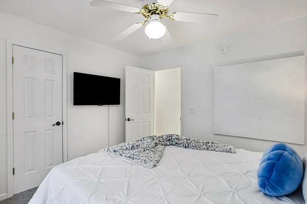 Queen bedroom with wall-mounted smart TV for winding down after the beach