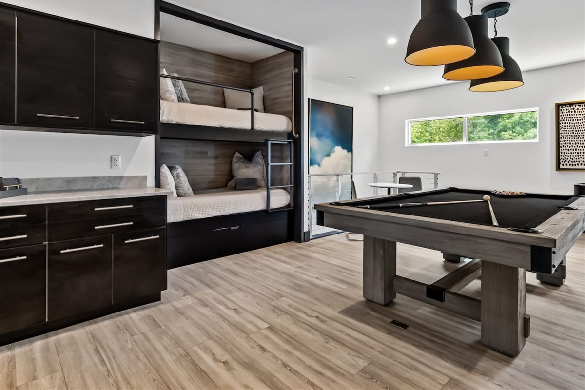 Pool table with beverage center and bunks in same room.