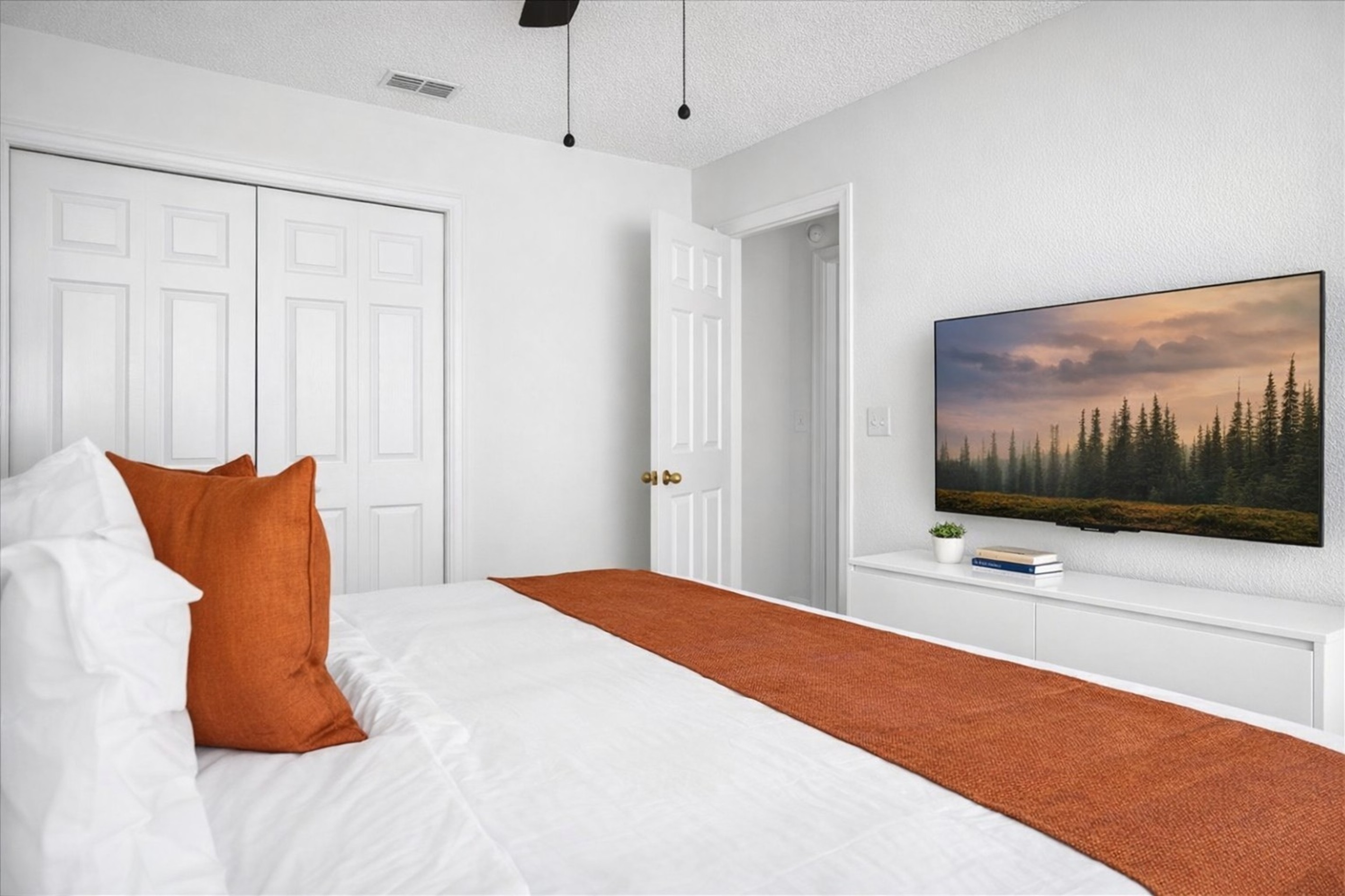 Modern KING bedroom with a 50" Roku television for streaming all of your favorites with warm orange accents.