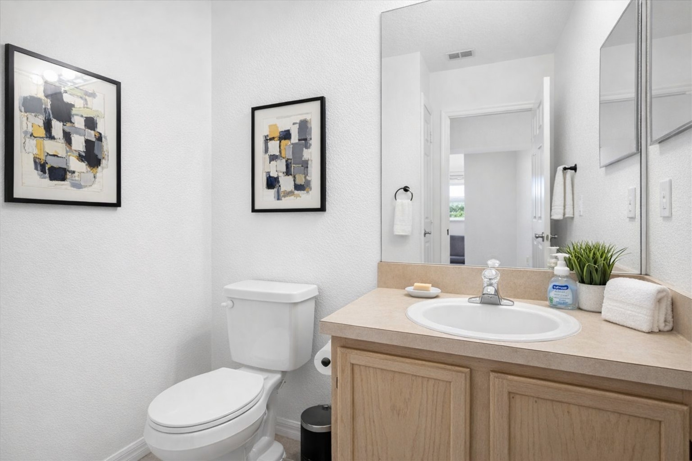Compact bathroom with a single sink vanity and modern abstract artwork.