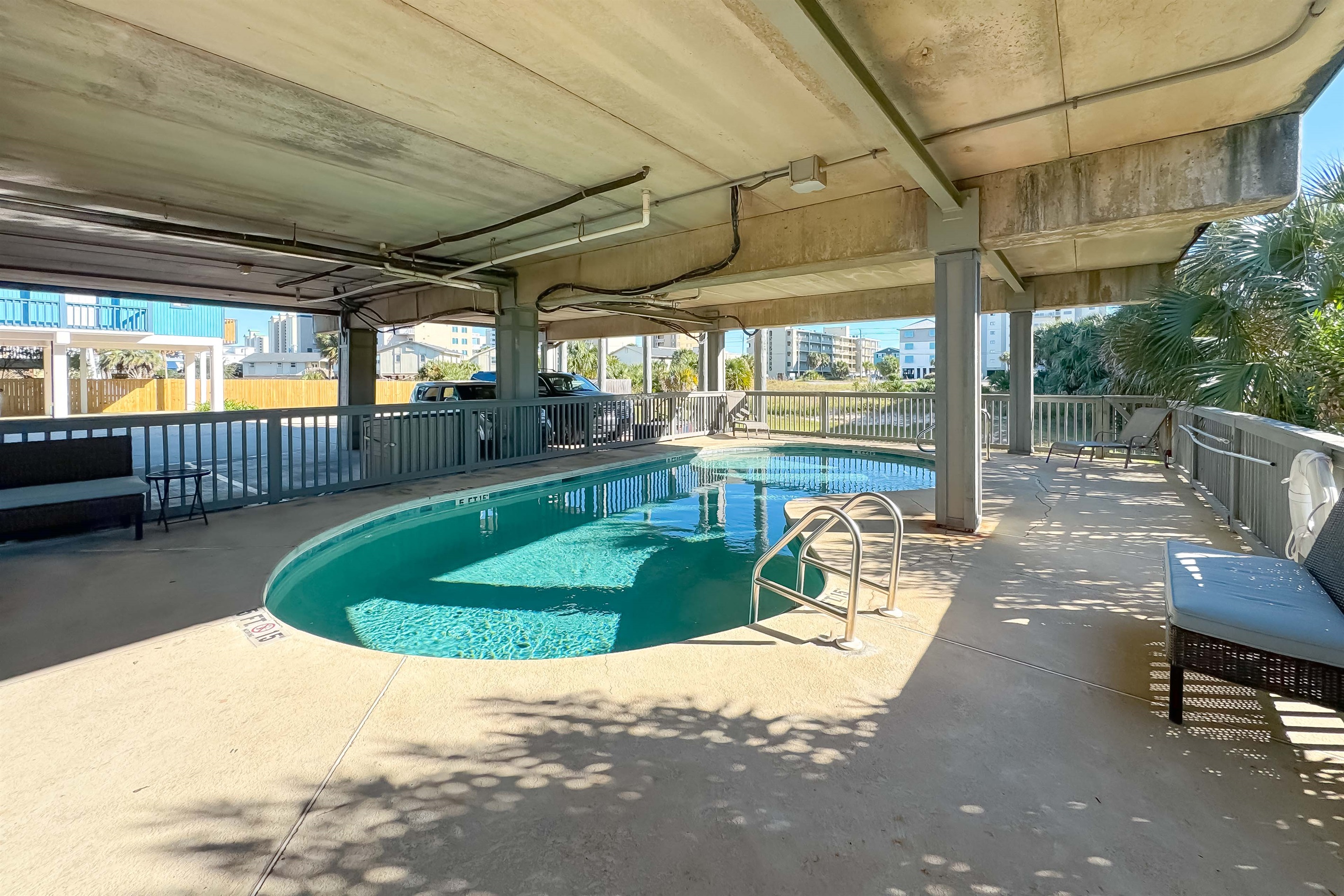 The pool is next to the parking spaces