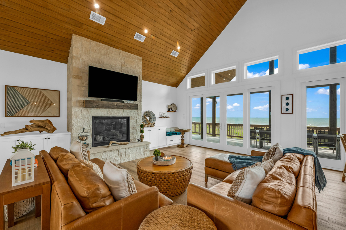 Cair Paravel: A stacked-stone fireplace and mounted TV anchor the living room, where leather sofas and a woven coffee table make the perfect spot to unwind after a day at the beach.