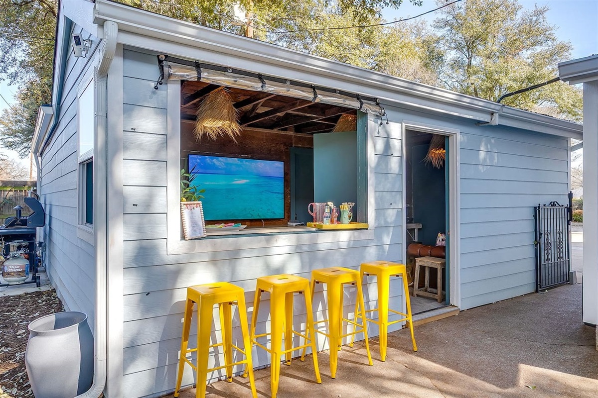 Outdoor bar with service window, lounge seating and TV