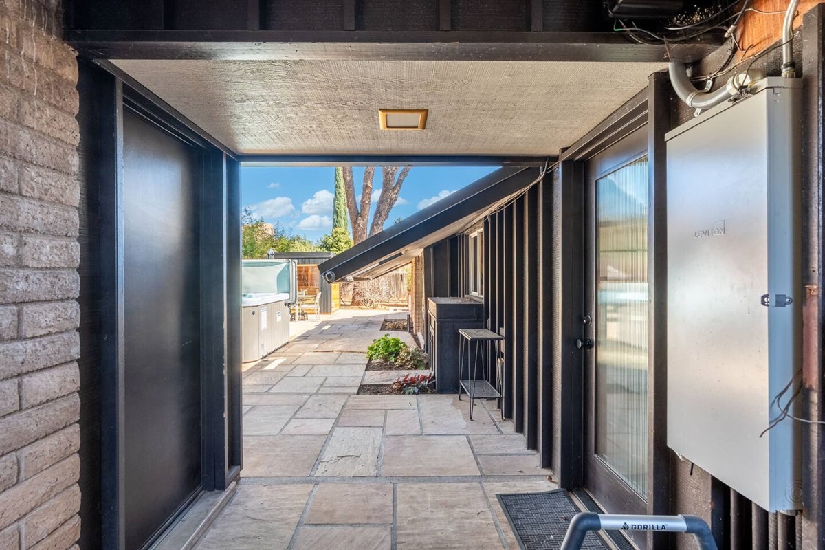 Covered breezeway with clean mid-century lines and private outdoor access, connecting the home’s living spaces to the serene patio and hot tub area for seamless indoor-outdoor flow.