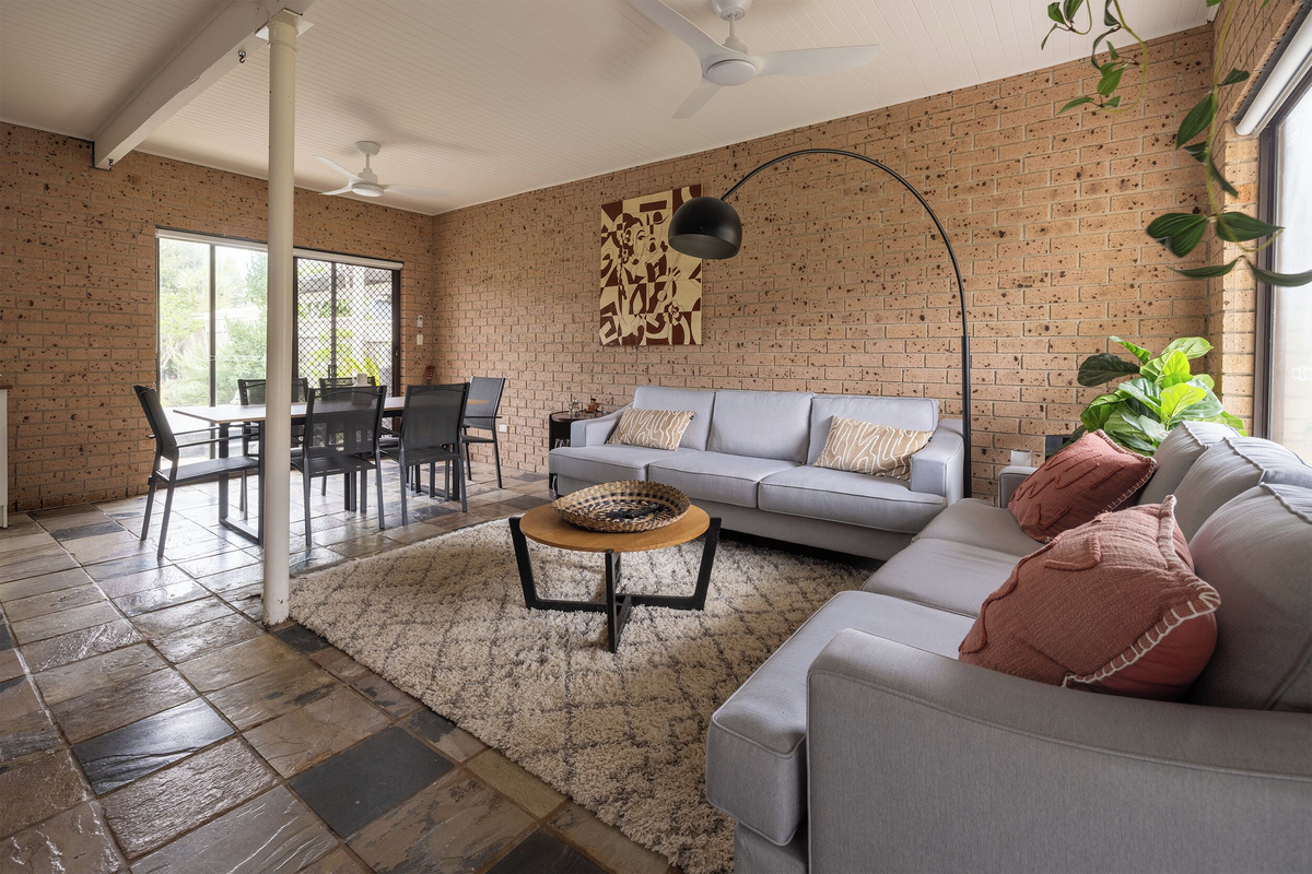Located near the main entrance, this downstairs living area features two comfortable sofas, a TV, ceiling fans, and a TV unit with books and board games.