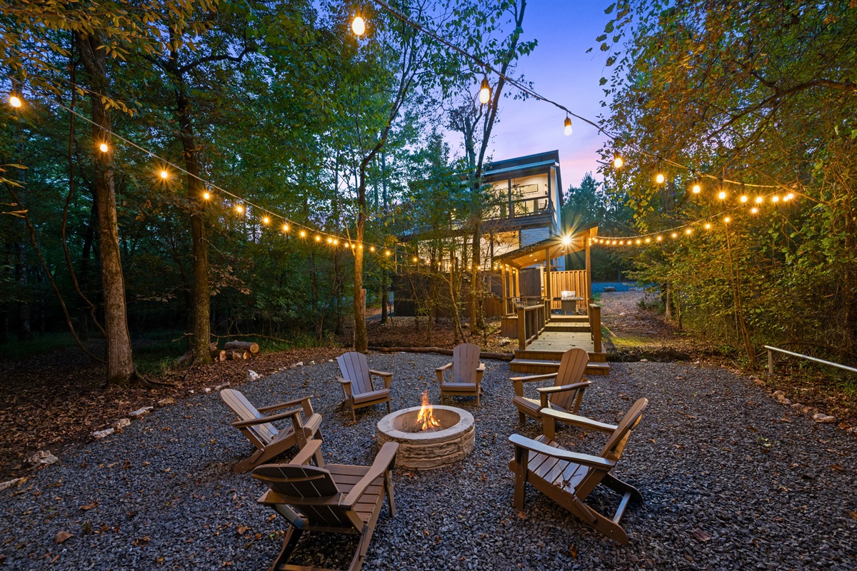 The fire pit area is surrounded by Adirondack chairs and soft lighting, making it an inviting place to gather after sunset.