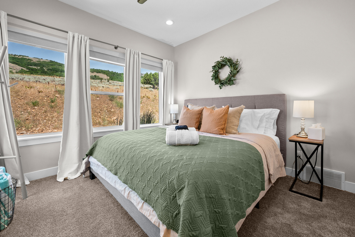 Peaceful lower-level king bedroom featuring soft linens, large windows, and a relaxing retreat after a day of skiing, hiking, or exploring.