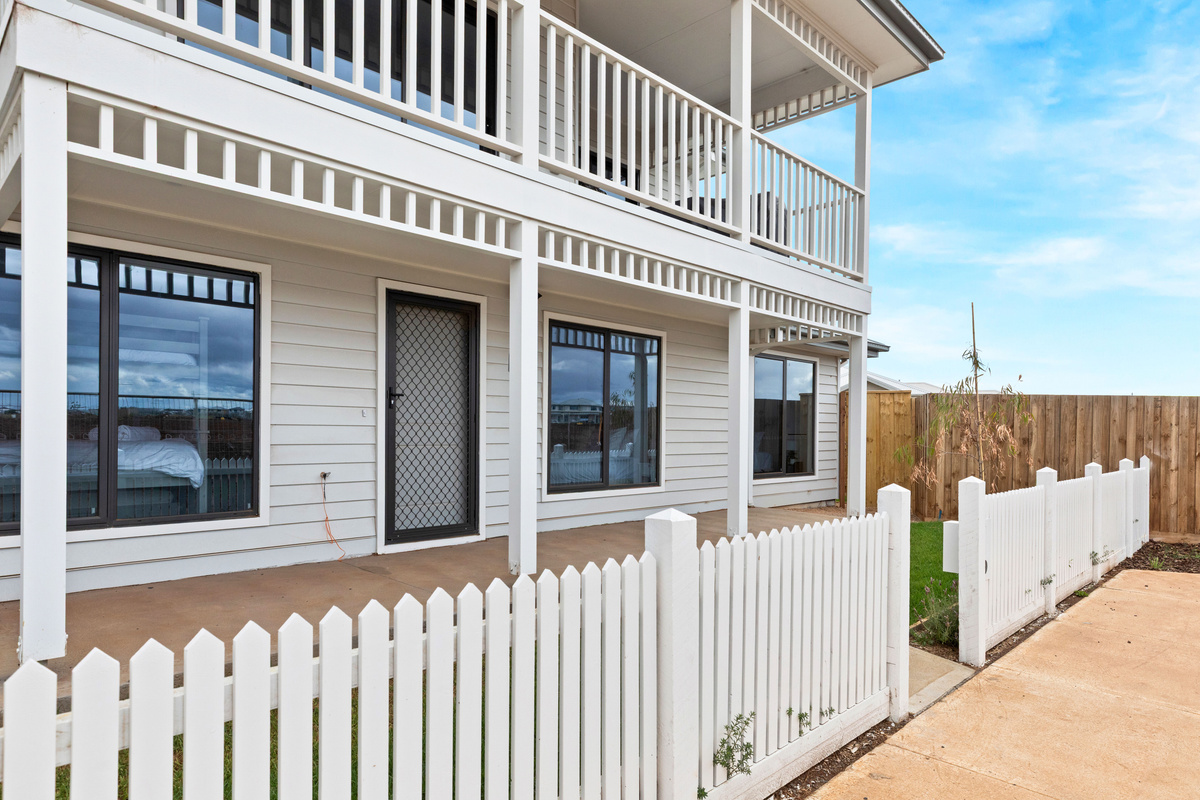 Front of the home with the covered ground-floor verandah, picket fence and the upstairs balcony above.