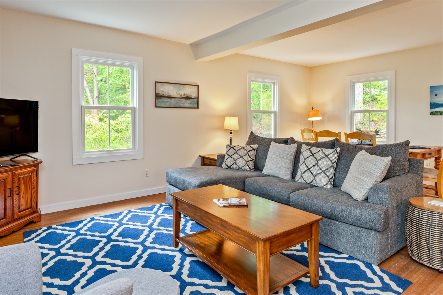 Relax in a bright living room with a large sliding door opening to the porch, surrounded by lush greenery and peaceful lake views.