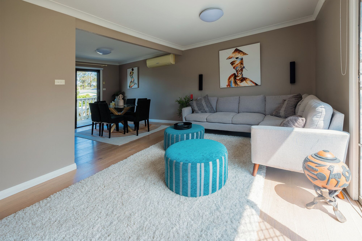 Enjoy a bright first-floor living space with a comfortable L-shaped sofa, TV with sound system, and seamless access to the front balcony.