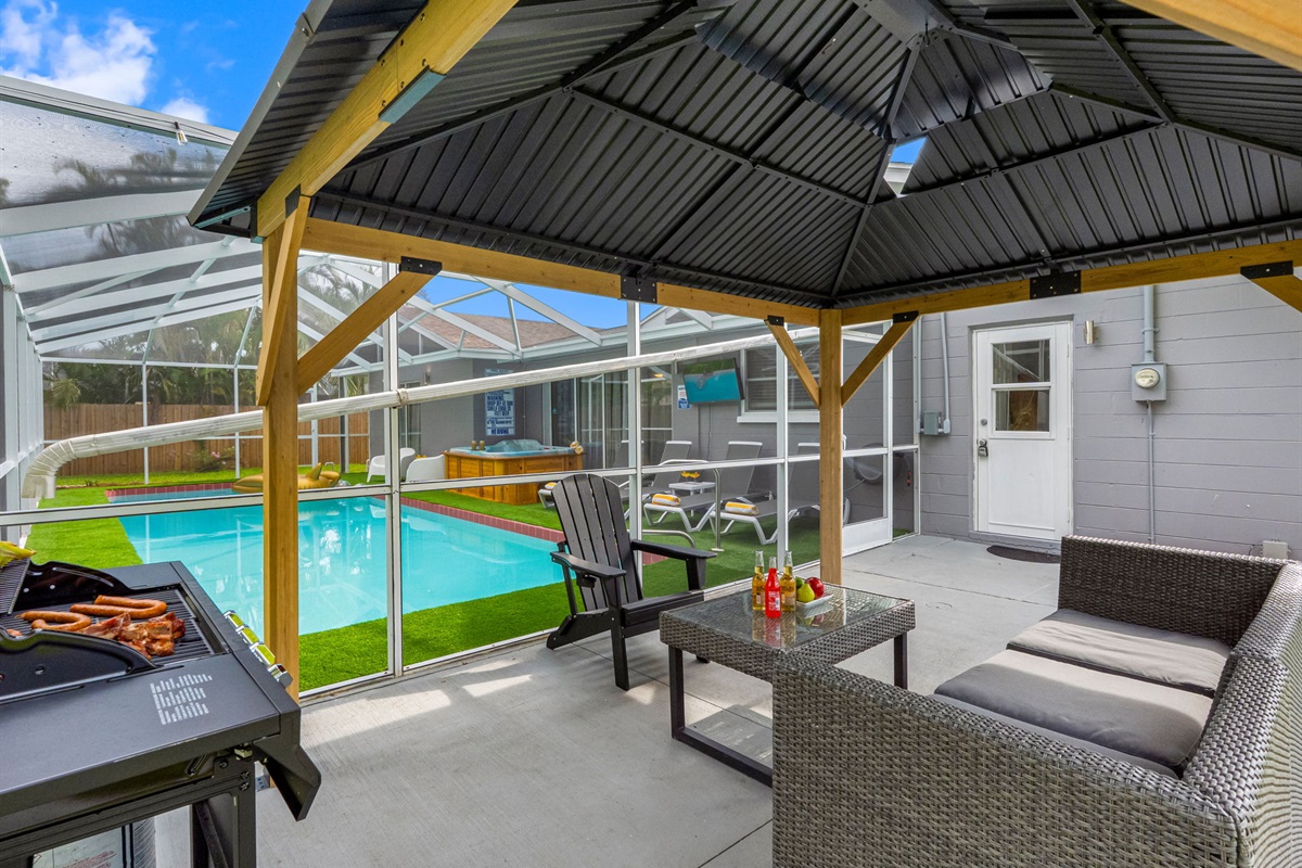 Relax in the shade under this modern gazebo, complete with cozy seating, a dining table, and easy access to the pool and spa.