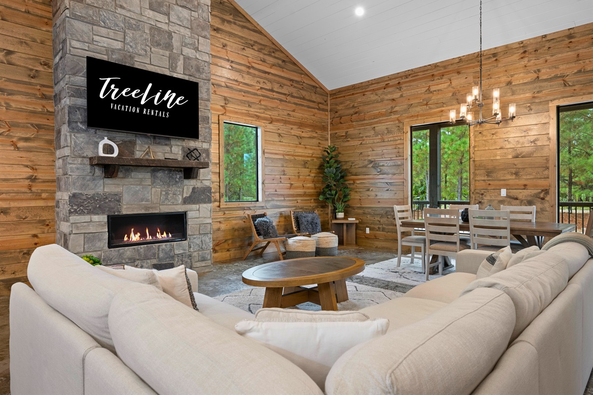 Spacious open-concept living area with vaulted ceilings and stone fireplace.