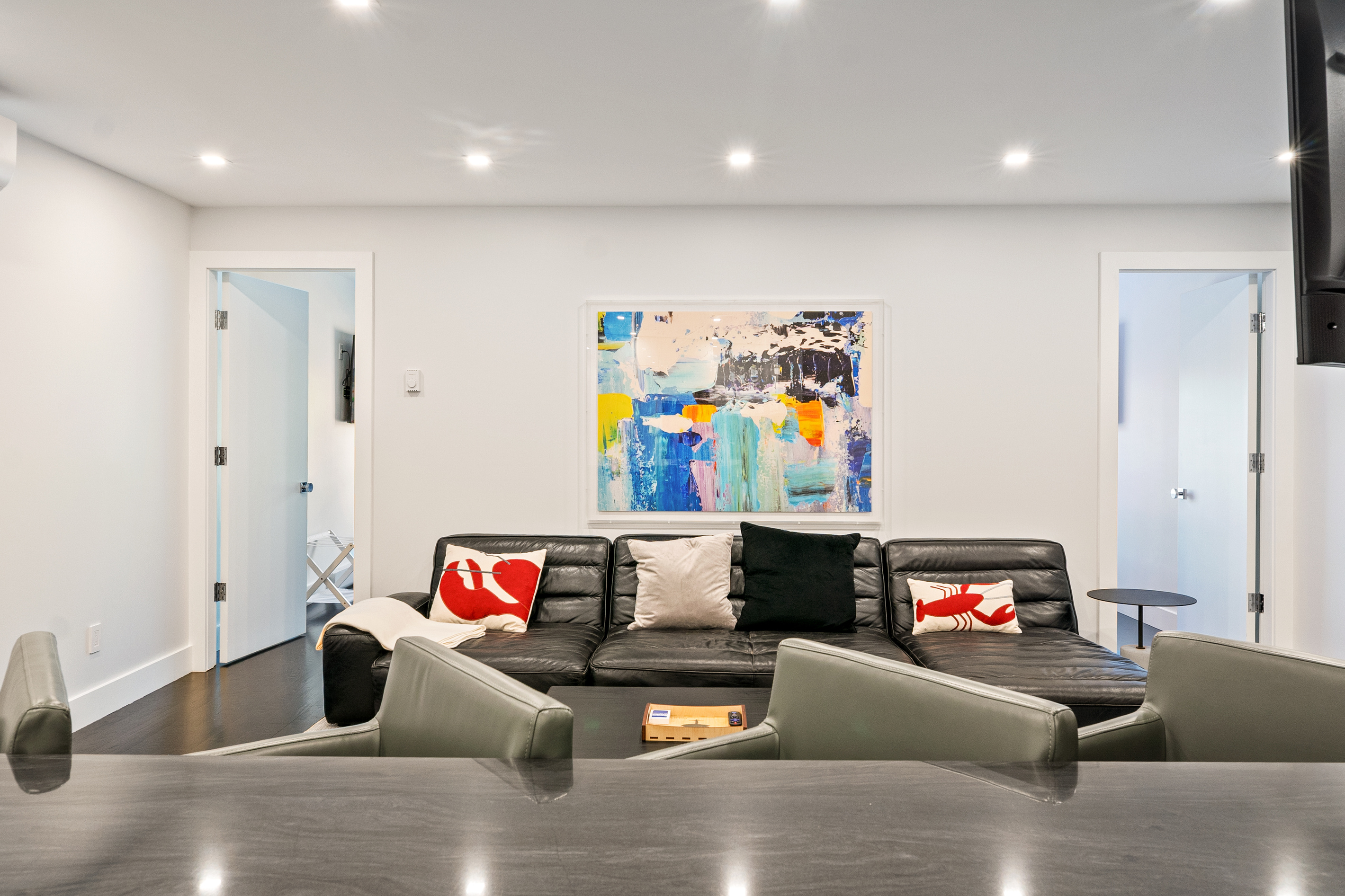 An open-concept layout connecting the kitchen counter to the main living area. Chat with friends or family sitting at the island while they relax on the leather sectional. A comfortable shared hub right in the center of downtown Bar Harbor.
