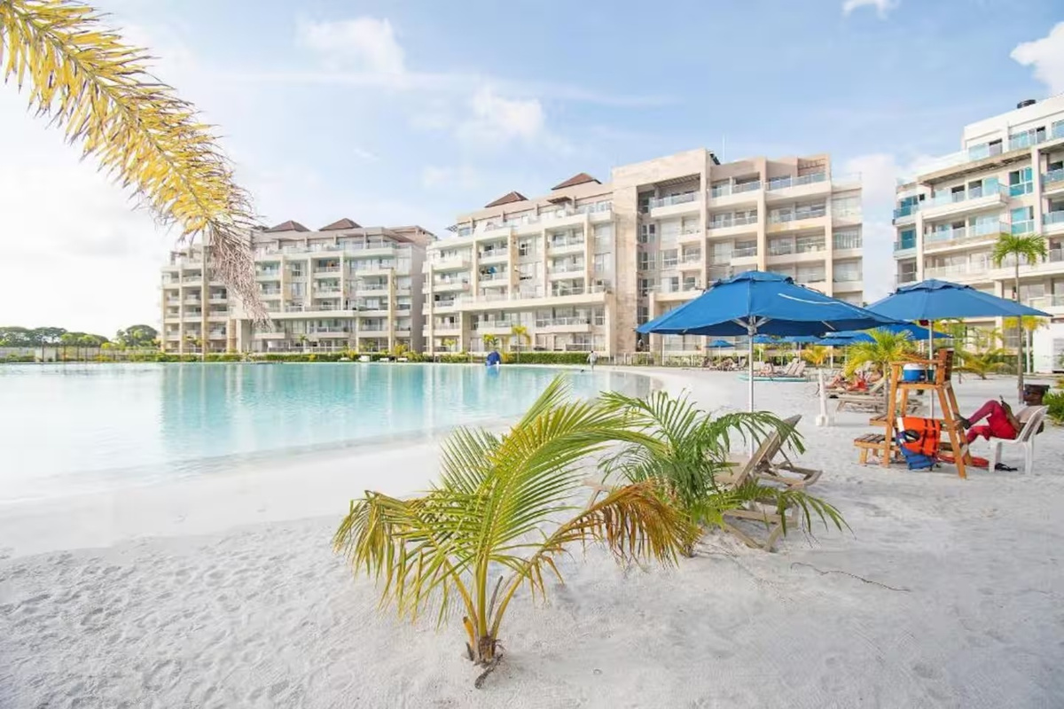 La piscina tipo laguna y los espacios exteriores rodeados de palmeras crean un ambiente tipo resort ideal para días soleados, descansos junto a la piscina y momentos relajados durante las vacaciones.