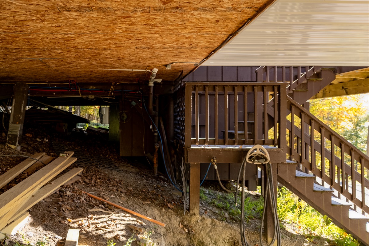 Under-deck view showing coarse terrain and structure — rustic base of cabin.