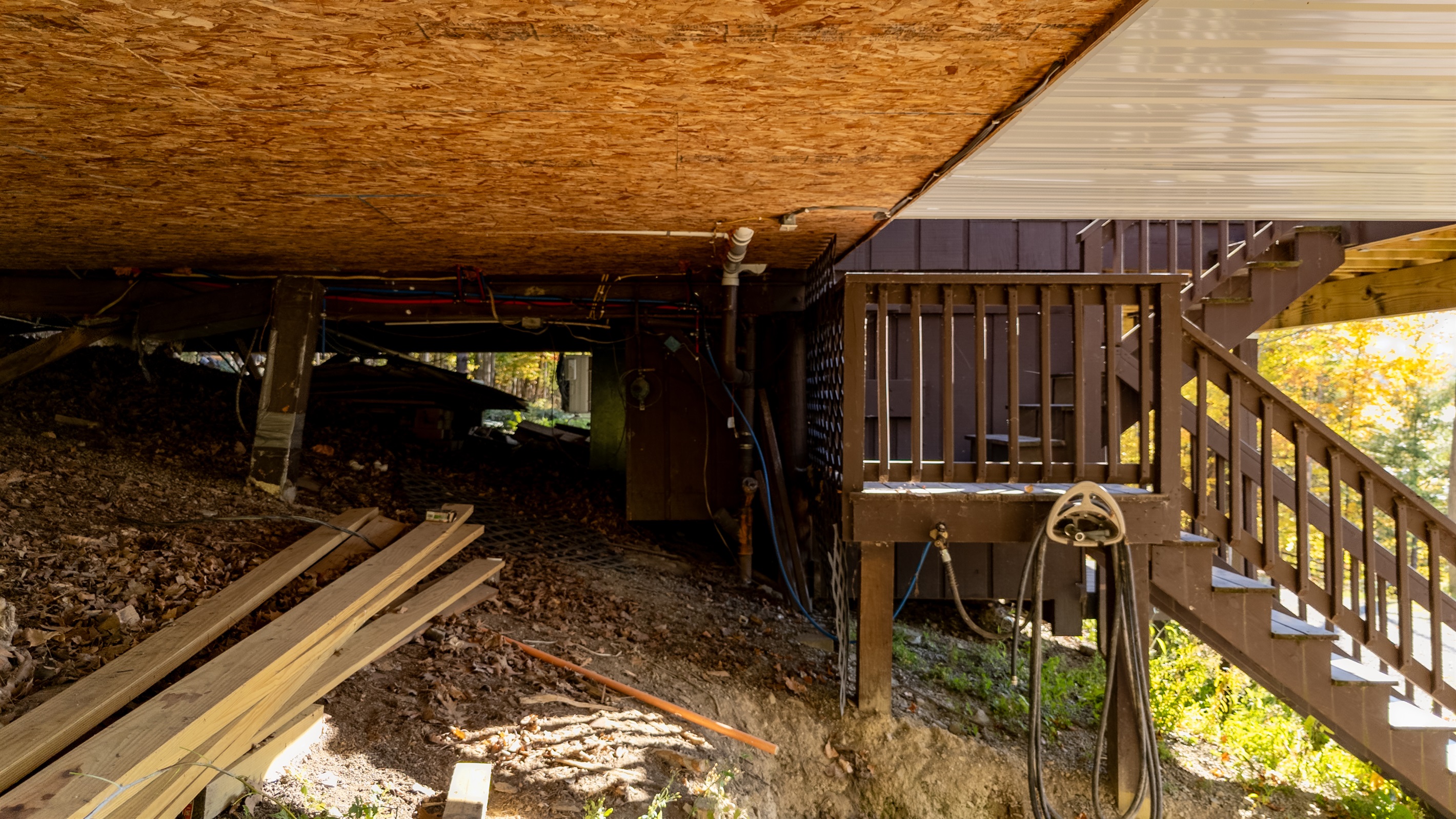 Under-deck view showing coarse terrain and structure — rustic base of cabin.
