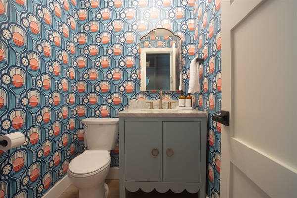 Fun half bath in the Locker Room with pickleball wallpaper and cheeky charm—because even bathroom breaks deserve good design