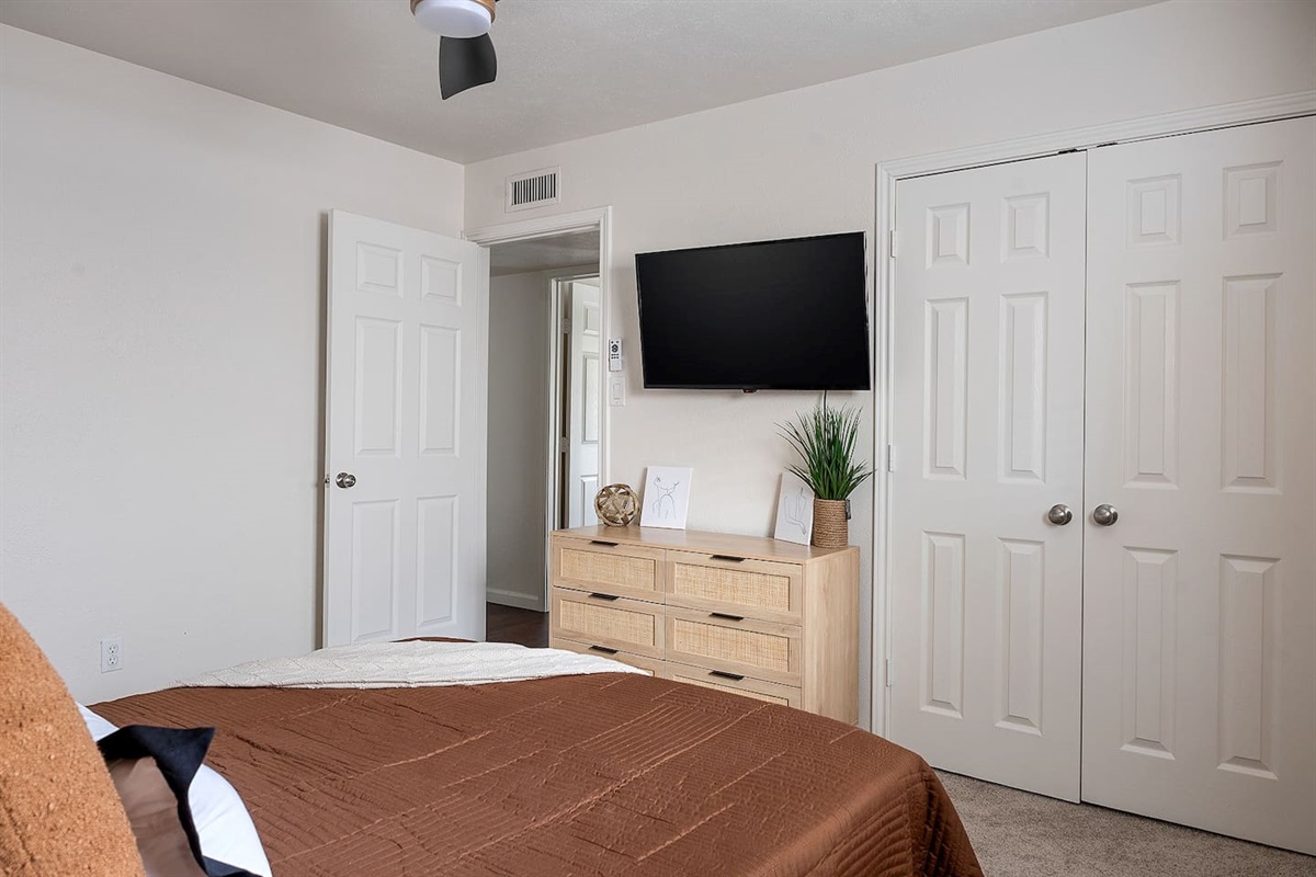 The bedroom is furnished with a sleek dresser and a wall-mounted TV, offering a modern and functional space for relaxation.