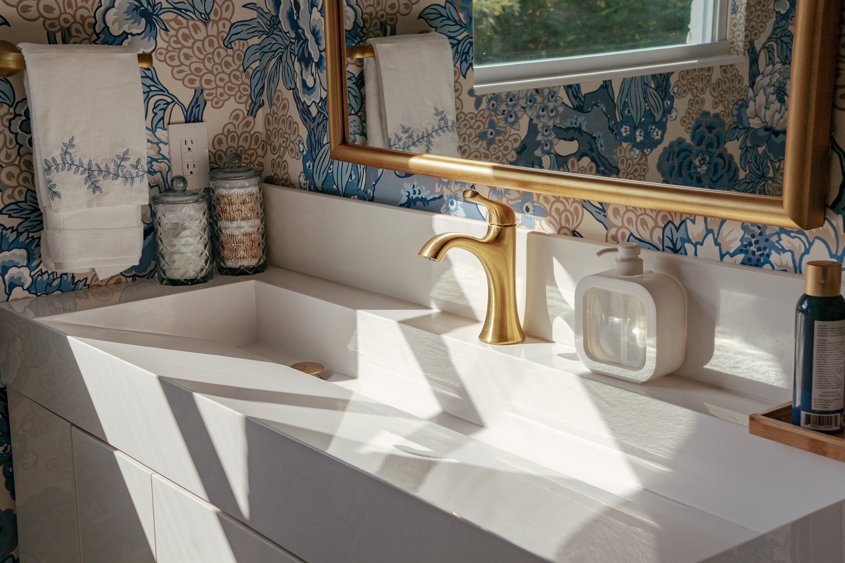 The shared full bathroom delights with colorful wallpaper and impeccable finishes.