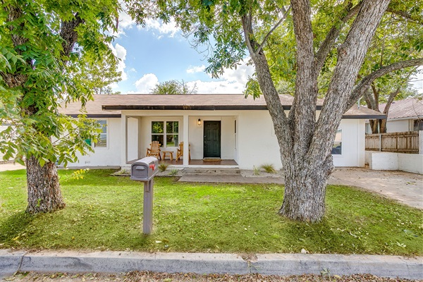 Welcoming front yard with mature trees and covered walkway