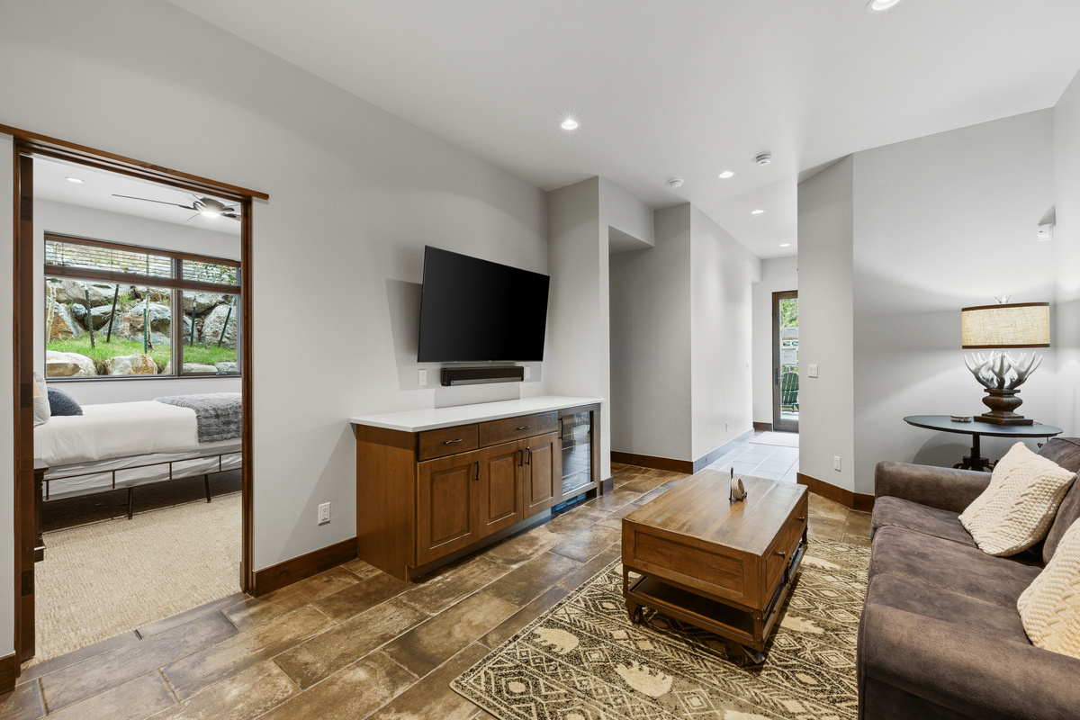 Lower level living area with large tv, wine refrigerator and Queen sofa sleeper. A full-sized twin bed is stored nearby (not shown) and can fit easily in this area. 