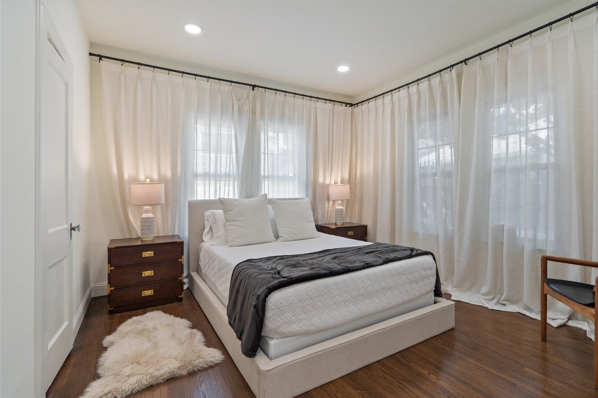 Bedroom 2 Queen Bed with hotel-style linens, extra pillows and blankets, room-darkening shades, and clothing storage. Private space with central AC and high-speed Wi-Fi. First floor, main house.