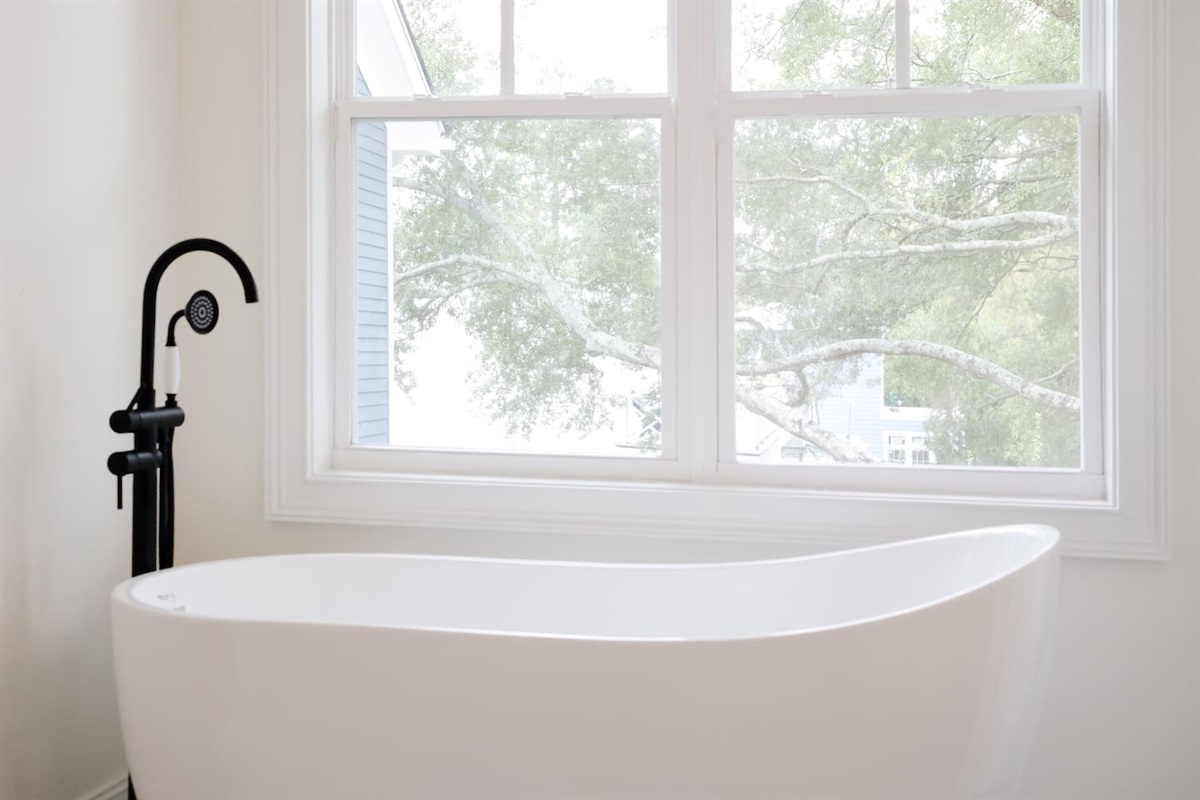The soaking tub is the star of the show in the primary bathroom. Enjoy a relaxing bath with views of the beautiful live oaks.