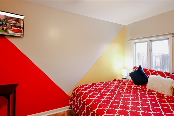 A bedroom painted with a cheerful palette of red, yellow, and white walls, creating a bright and inviting space that stimulates creativity and comfort.
