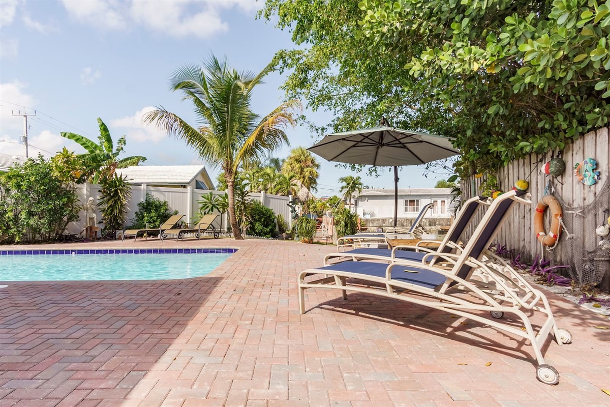 Idyllic outdoor recreation space. In the evening multicolored pool lights and Edison-bulb string lighting create a magical and romantic atmosphere around the patio and tropical backyard!