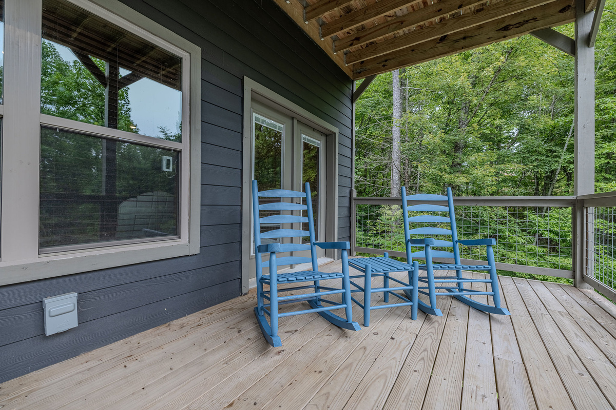 The covered deck offers a quiet place for morning coffee, evening drinks, and wooded mountain views.