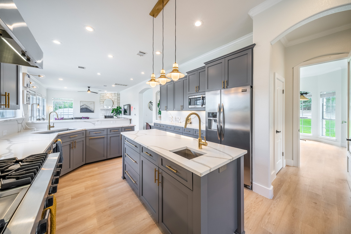 Sleek kitchen island illuminated by a statement chandelier.