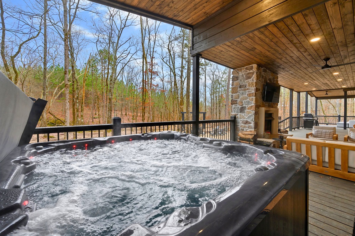 The covered hot tub sits right off the back deck, offering a relaxing spot to soak while taking in peaceful wooded views.c