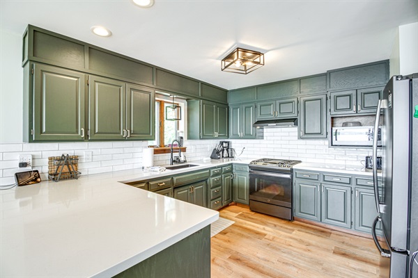 Bright kitchen with white countertops, gas range, and tile backsplash